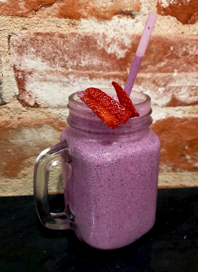 Blueberry smoothie, topped with a fresh strawberry.